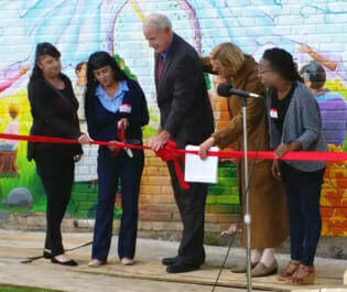 Milwaukee Christian Center staff members Juanita Valcarcel and Arlene Gonzales with Mayor Tom Barrett, executive director Karen Higgins and artist Tia Richardson at the ribbon cutting in front of the mural at Milwaukee Christian Center’s new gathering space.
