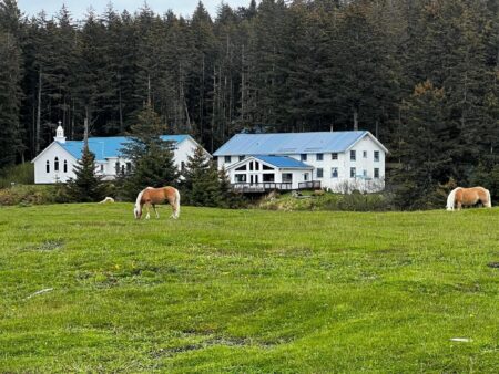 Photo of Smith Chapel and the dormitory at Camp Woody on Woody Island, Alaska, with horses in the foreground.