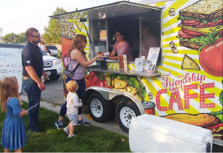 Picture showing customers buying something good to eat from the Friensship House food trailer.