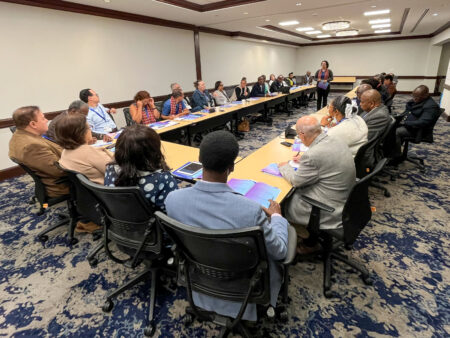 Photo of Rev. Abigail Media Betancourt facilitating a conversation among a diverse group of clergy at the Allelon gathering of MBMM.